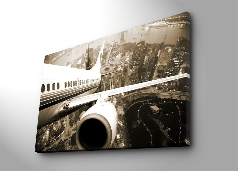 Canvastavla 70x100 cm - Ett flygplan som svävar över en stad i skymningsljus, Svart / Vit / Grå