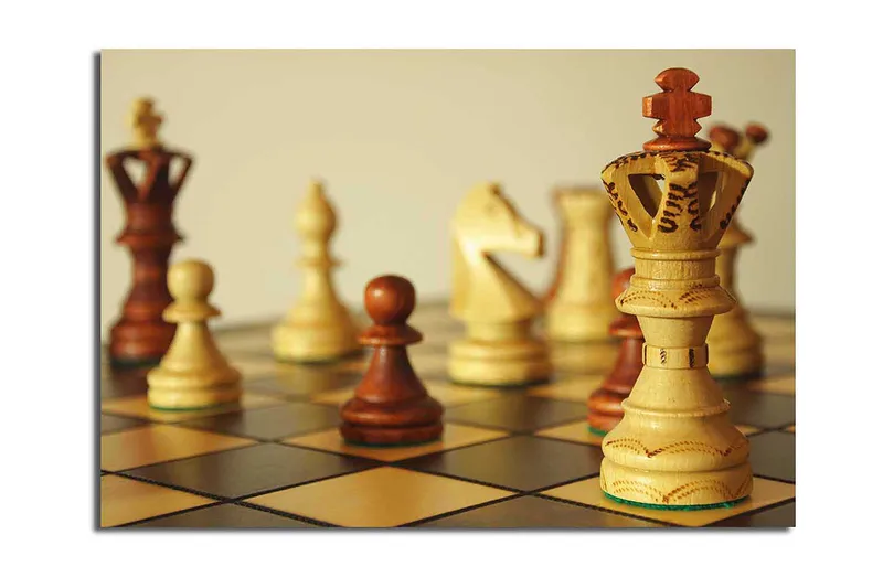 Canvastavla 70x100 cm - Ett schackbräde med träpjäser i fokus, där drottningen står framträdande, Ljusbrun / Mörkbrun / Beige