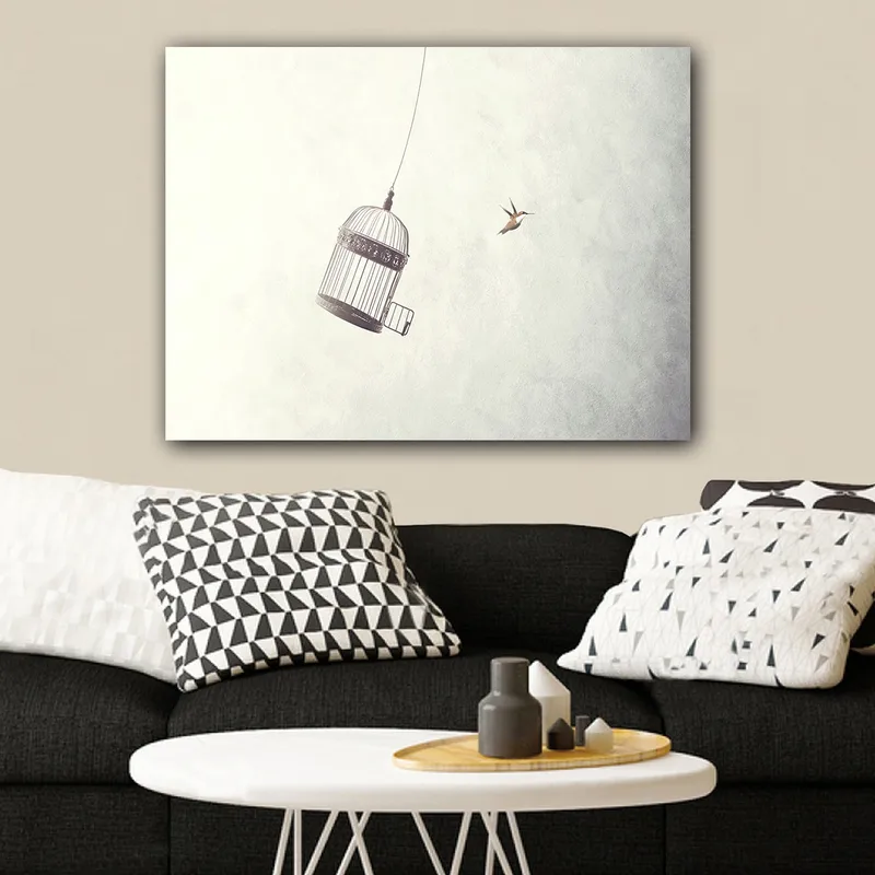 Canvastavla 70x100 cm - Fågelbur hänger i luften med en fågel som flyger i närheten, Grå / Svart / Vit