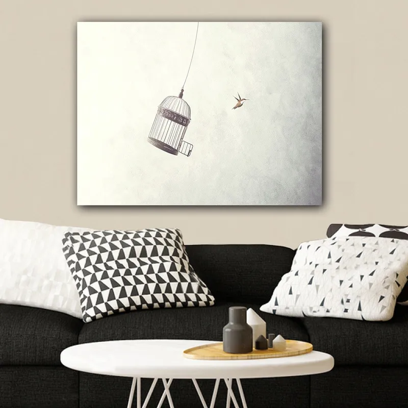 Canvastavla 70x100 cm - Fågelbur hänger i luften med en fågel som flyger i närheten, Grå / Svart / Vit