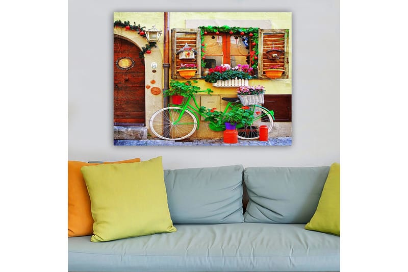 Canvastavla 70x100 cm - Färgglad cykel prydd med blommor och krukor framför en charmig vägg med fönster och dekorationer - Grön / Rosa / Orange - Inredning & dekor - Tavlor & konst - Canvastavla