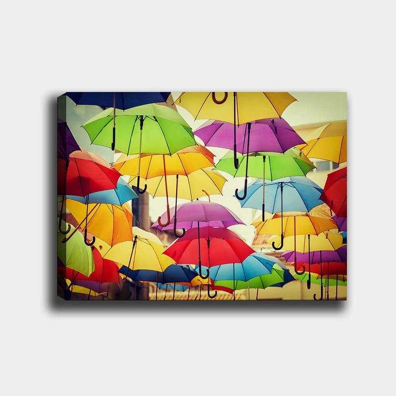 Canvastavla 70x100 cm - Färgglada paraplyer som hänger i luften skapar en livlig och lekfull atmosfär, Grön / Gul / Röd