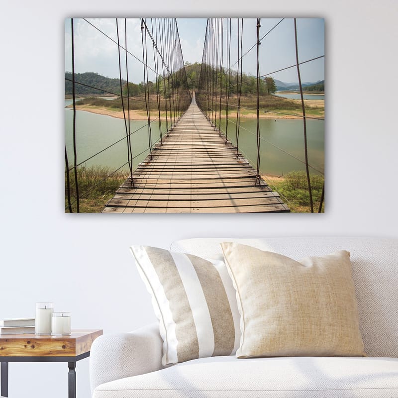 Canvastavla 70x100 cm - Hängbro som sträcker sig över en stilla sjö, omgiven av grönskande kullar, Grön / Brun / Beige