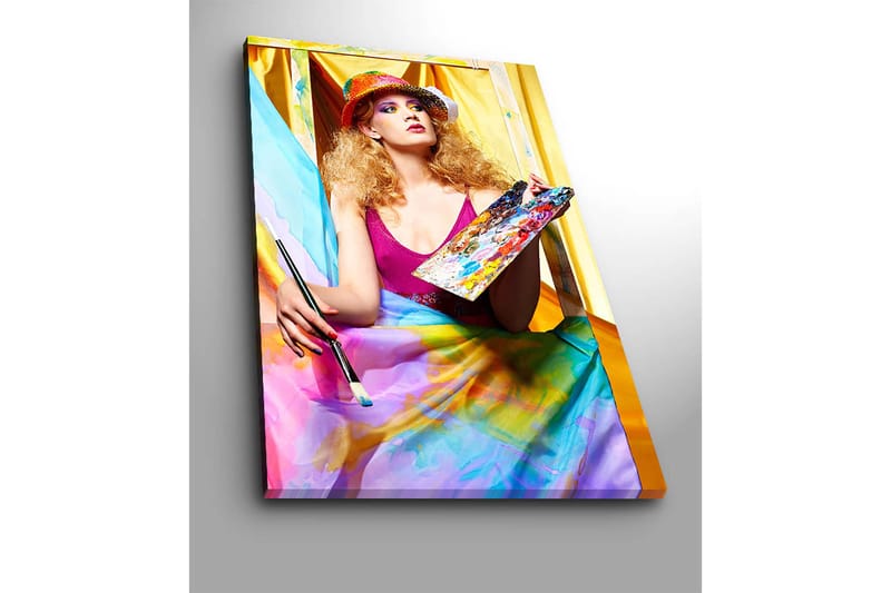 Canvastavla 70x100 cm - Kreativ kvinna som målar med en palett i handen, omgiven av färgglada tyger - Rosa / Blå / Gul - Inredning & dekor - Tavlor & konst - Canvastavla