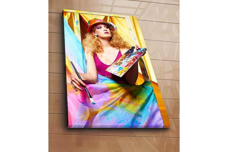 Canvastavla 70x100 cm - Kreativ kvinna som målar med en palett i handen, omgiven av färgglada tyger - Rosa / Blå / Gul - Inredning & dekor - Tavlor & konst - Canvastavla