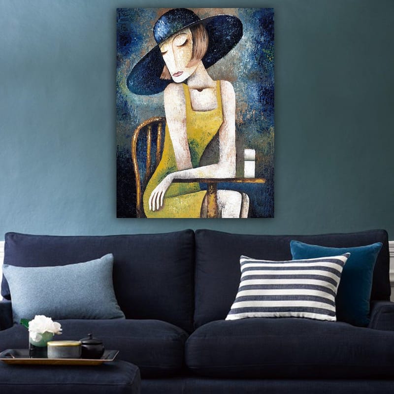Canvastavla 70x100 cm - Kvinna i en gul klänning sitter vid ett bord med en vit kopp, iförd en stor svart hatt - Gul / Svart / Blågrön - Inredning & dekor - Tavlor & konst - Canvastavla