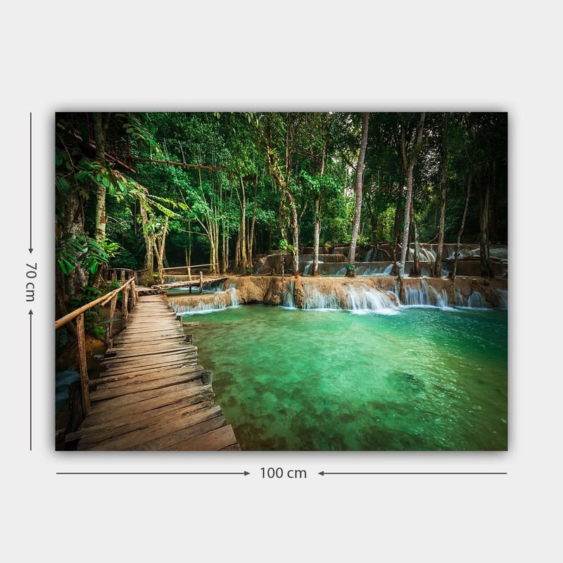 Canvastavla 70x100 cm - Lugn och naturskön plats med en träbro som leder över en klar, turkos vattenfallspool omgiven av frodig grönska - Turkos / Grön / Brun - Inredning & dekor - Tavlor & konst - Canvastavla