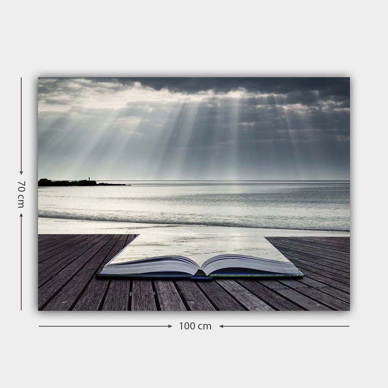 Canvastavla 70x100 cm - Öppen bok som ligger på en träbrygga vid havet, omgiven av mjuka ljusstrålar från en molnig himmel - Grå / Blå / Vit - Inredning & dekor - Tavlor & konst - Canvastavla