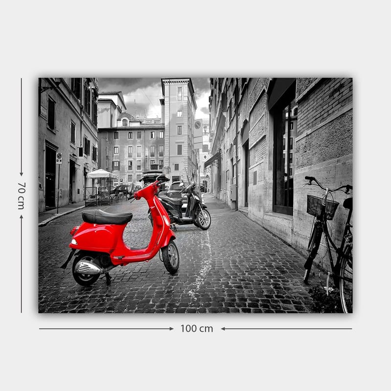 Canvastavla 70x100 cm - Röd scooter står i en svartvit stadsmiljö med kullerstensgator och byggnader - Röd / Svart / Grå - Inredning & dekor - Tavlor & konst - Canvastavla