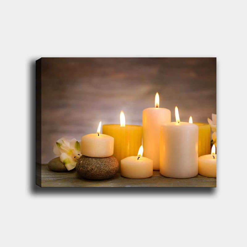 Canvastavla 70x100 cm - Samling av tända ljus i olika former och storlekar, omgivna av stenar och en blomma, Gult / Vitt / Beige