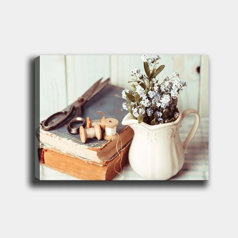 Canvastavla 70x100 cm - Stillsam komposition av en kanna med blommor, en bok och syverktyg, Ljusblå / Beige / Grön