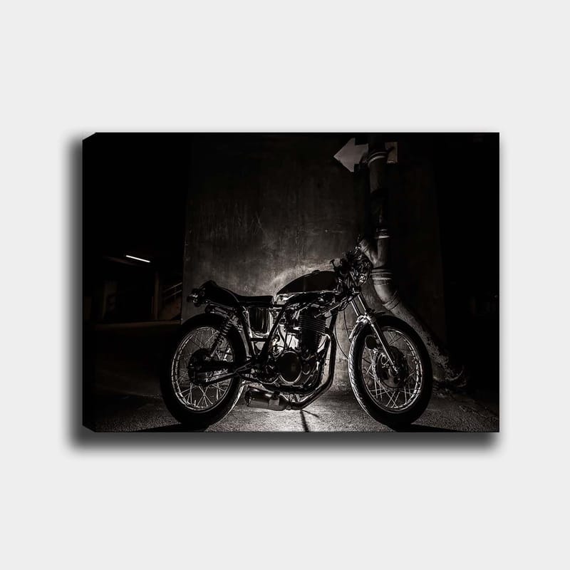 Canvastavla 70x100 cm - Stilren motorcykel i en urban miljö med fokus på detaljer och skuggor, Svart / Grå
