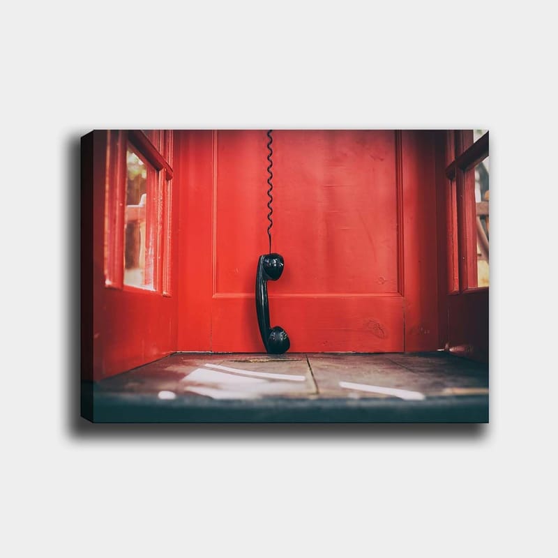 Canvastavla 70x100 cm - Svart telefon hänger i en röd telefonkiosk, Röd / Svart