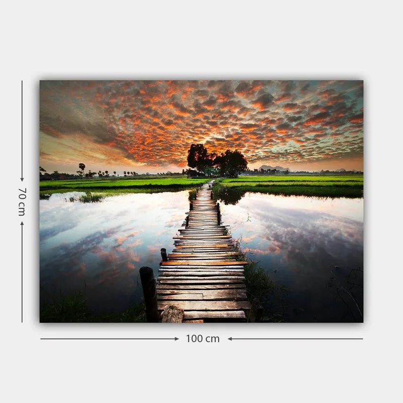 Canvastavla 70x100 cm - Träbro som sträcker sig över en spegelblanka vattenyta, omgiven av grönskande landskap och en dramatisk solnedgång - Orange / Grön / Blå - Inredning & dekor - Tavlor & konst - Canvastavla