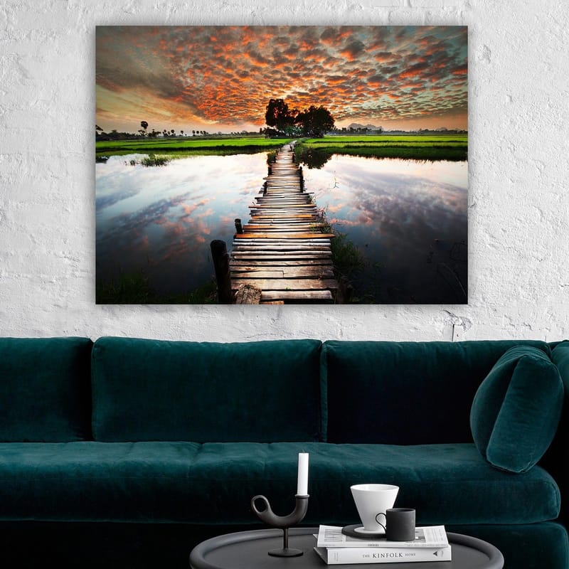 Canvastavla 70x100 cm - Träbro som sträcker sig över en spegelblanka vattenyta, omgiven av grönskande landskap och en dramatisk solnedgång - Orange / Grön / Blå - Inredning & dekor - Tavlor & konst - Canvastavla