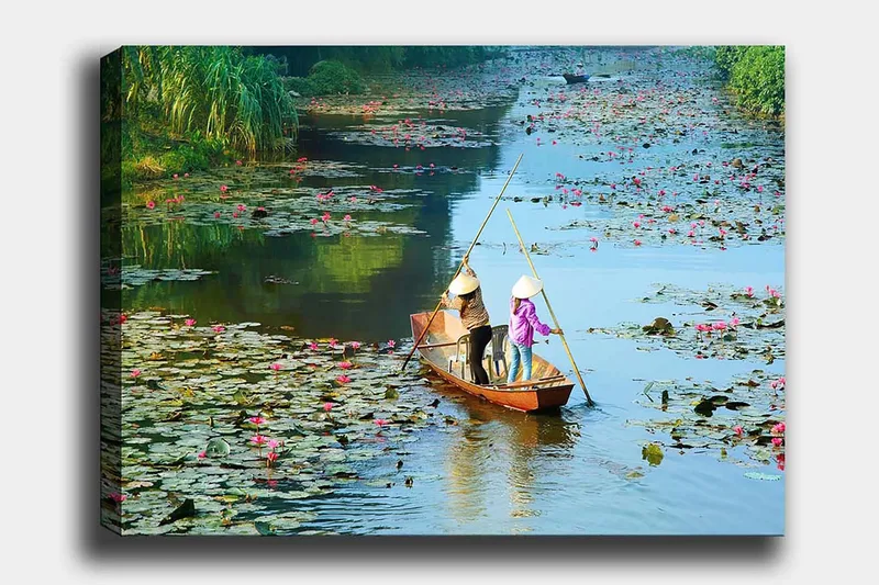 Canvastavla 70x100 cm - Två personer som paddlar en båt genom en sjö med vattenliljor och blommor, Grön / Rosa / Blå