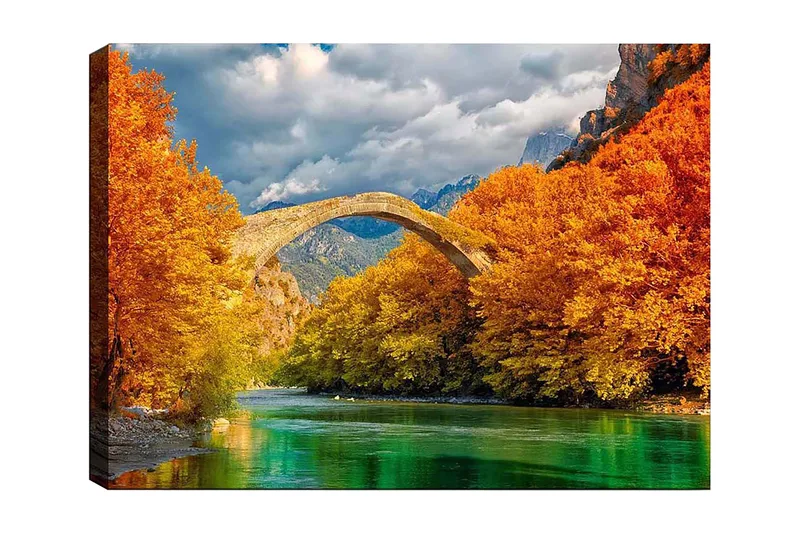 Canvastavla 70x100 cm - Vacker höstlandskap med en gammal stenbro som sträcker sig över en glittrande flod omgiven av färgglada träd, Orange / Grön / Blå