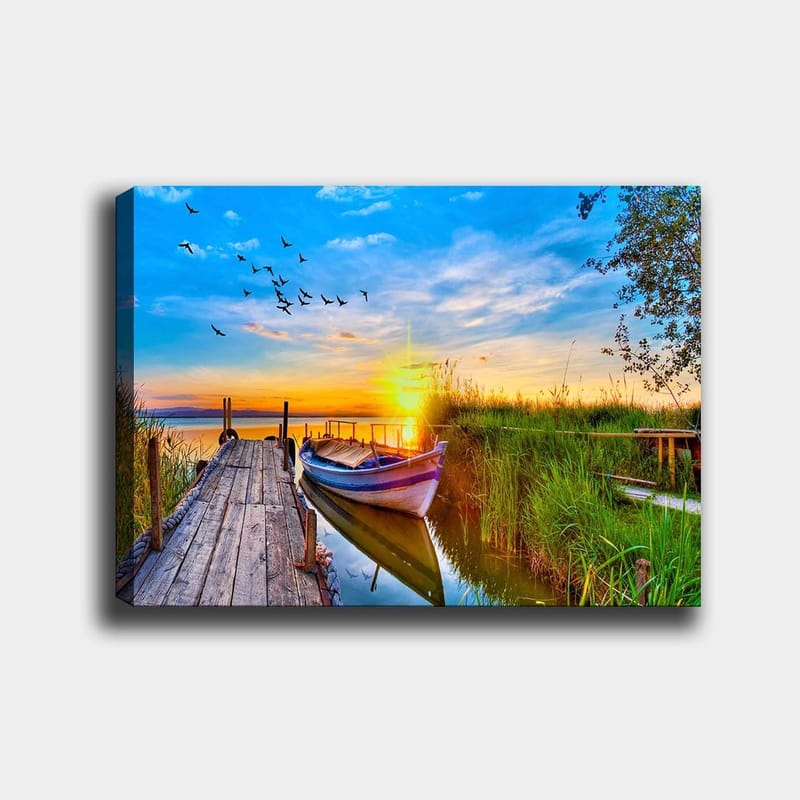 Canvastavla 70x100 cm - Vacker solnedgång över en stilla sjö med en båt vid en träbrygga omgiven av grönska, Blå / Orange / Grön