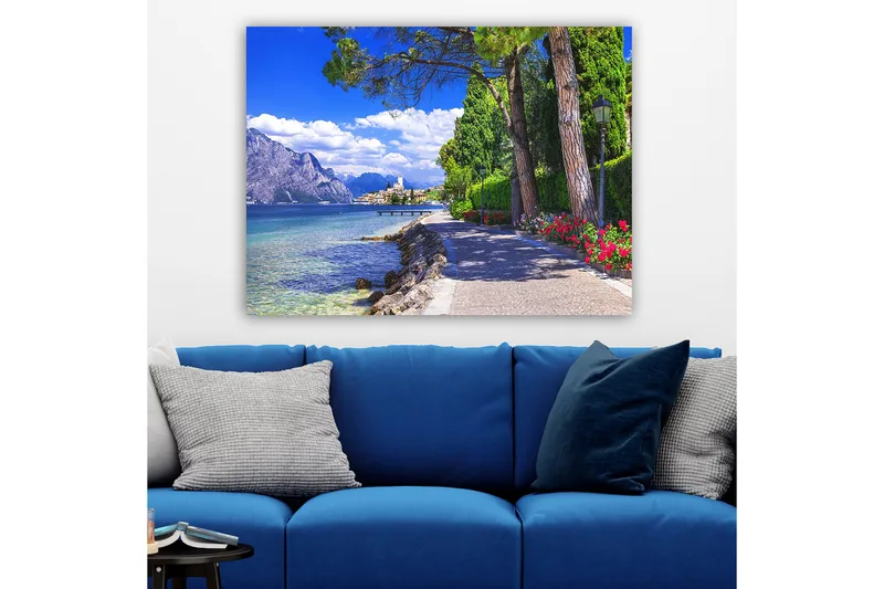 Canvastavla 70x100 cm - Vacker strandpromenad med träd och blommor vid en sjö, omgiven av berg och en pittoresk stad i bakgrunden - Blå / Grön / Röd - Inredning & dekor - Tavlor & konst - Canvastavla