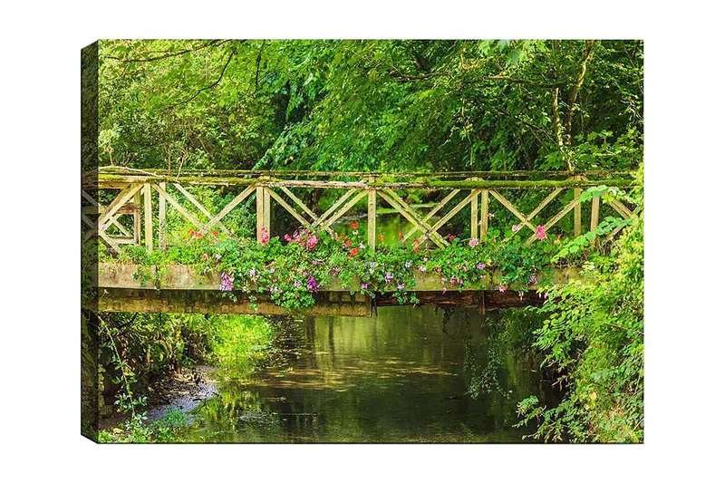 Canvastavla 70x100 cm - Vacker träbro omgiven av grönska och blommor vid en stilla vattenyta, Grön / Rosa / Brun