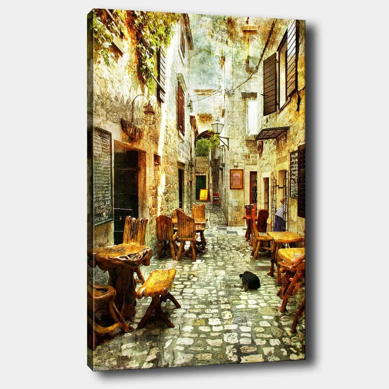 Canvastavla 70x100 cm - Pittoresk gränd med träbord och stolar, omgiven av gamla stenhus, Brun / Grå / Grön
