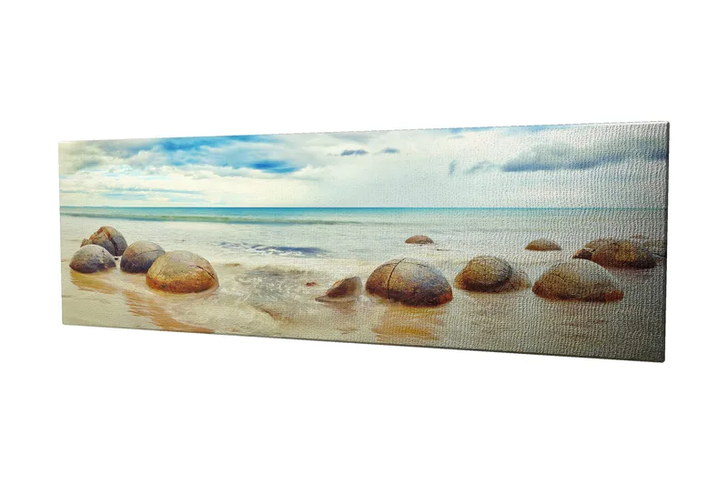 Canvastavla 80x30 cm - Runda stenar vid en strand med hav och himmel i bakgrunden, Blå / Beige / Grå