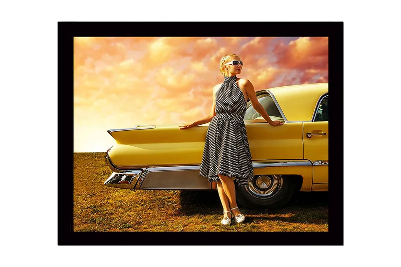 Inramad Canvastavla i trä - 41x56 cm - Kvinna i prickig klänning som lutar mot en vintage bil, Gul / Svart / Vit